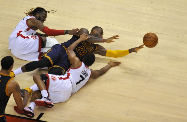epa05325885 Cleveland Cavaliers forward LeBron James tries to pass the ball after colliding with Toronto Raptors forward DeMarre Carroll (L) and guard Kyle Lowry during the fourth quarter of game four in the NBA Eastern Conference basketball finals at the Air Canada Center in Toronto, Canada, 23 May 2016. The Raptors defeated the Cavaliers 105-99. EPA/WARREN TODA CORBIS OUT