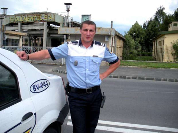 Celebrul polițist brașovean Marian Godină, sprijinit de masina de poliție, în dreptul Uzinei Rulmentul S.A.