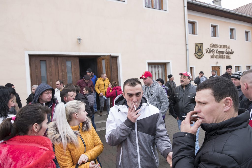 Zeci de locuitori ai comunei Ditrău vorbesc în fața căminului cultural după terminarea adunării sătești
