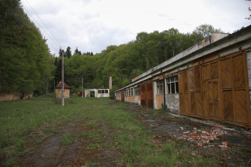 Ruinele fostei fabrici de conserve, iar în fundal este intrarea în mina care s-a închis în anul 1964