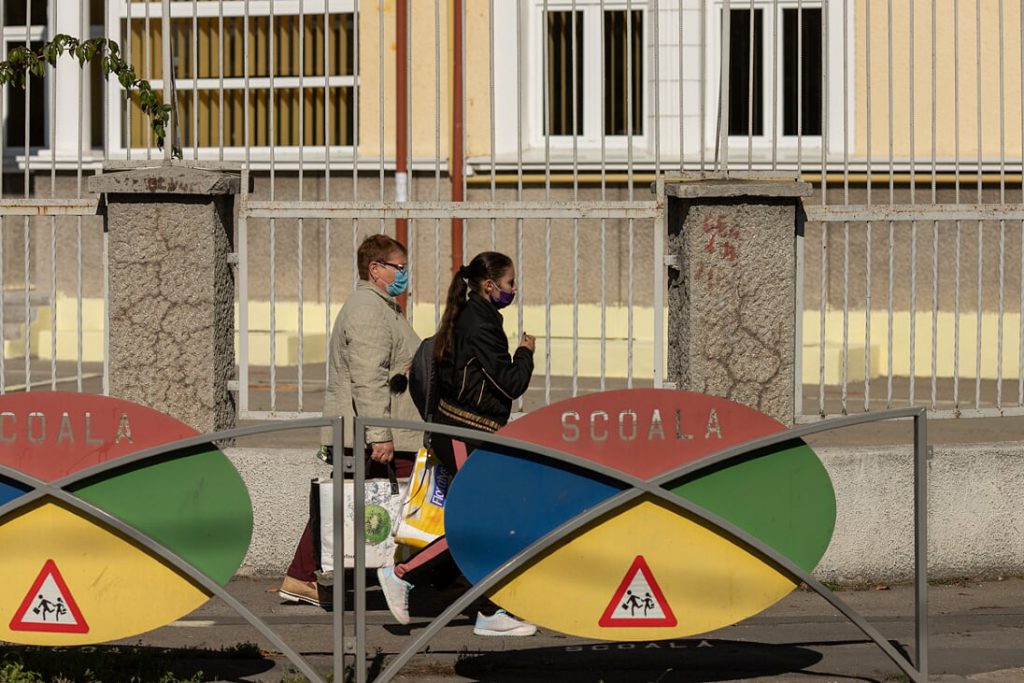 Două femeie trec prin fața unei școli, purtând mască de protecție. Foto: Vlad Chirea