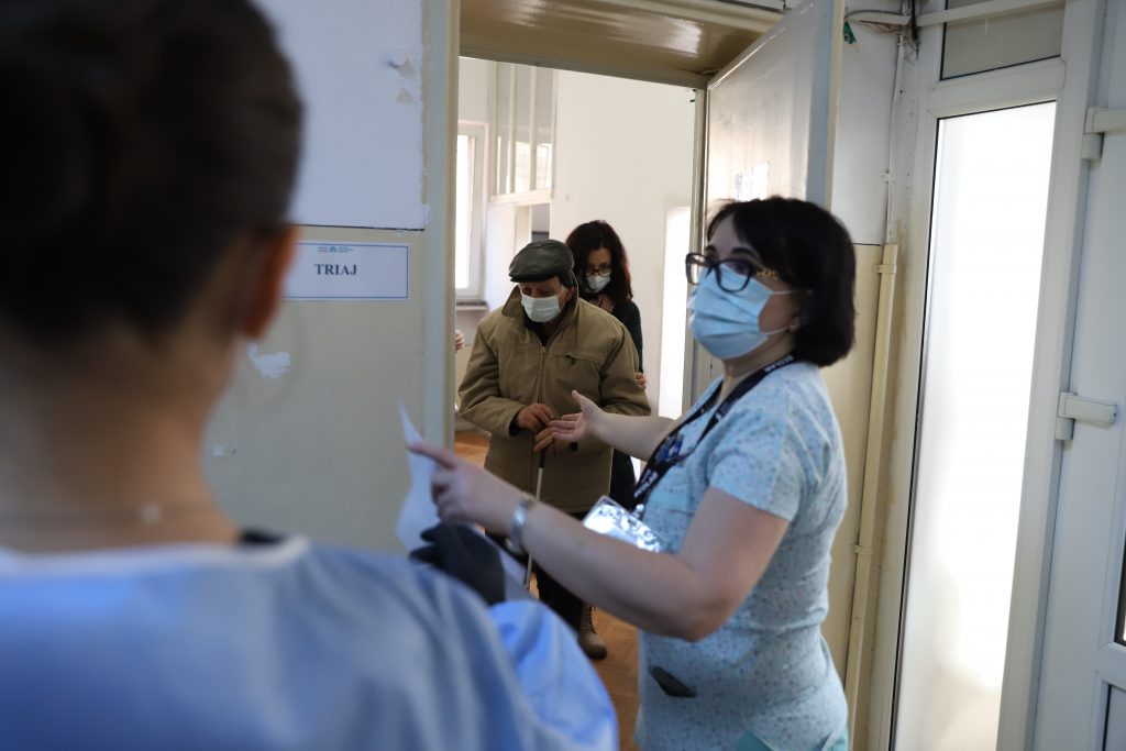 O asistentă îi îndrumă pe oameni în sălile de vaccinare