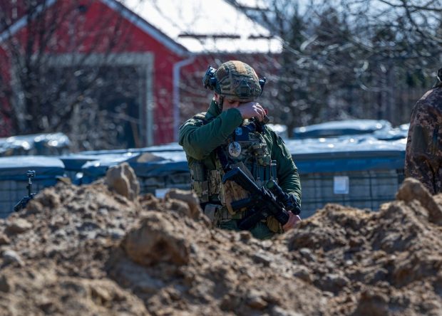 Soldat ucrainean fotografiat plângând în fața unei gropi comune din Bucha