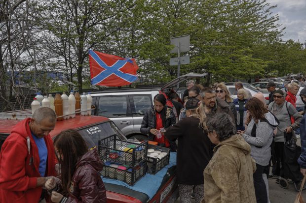 Locuitorii rămași în Mariupol stau la cozi pentru a primi pachete mici cu mâncare. Unii leșină așteptând