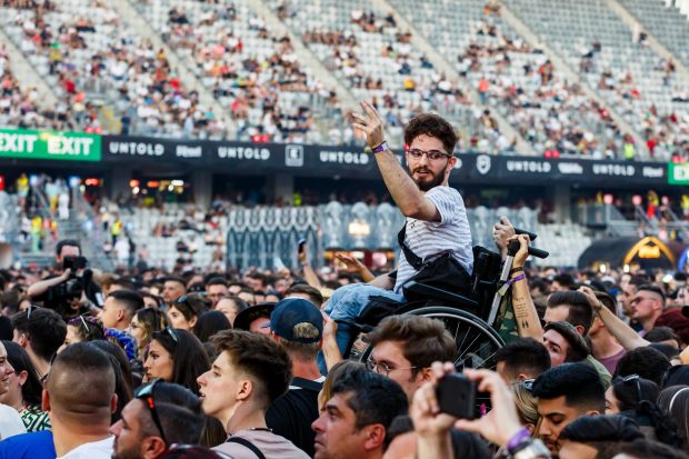 Fotografia zilei la UNTOLD. Tânăr în scaun cu rotile, ridicat desupra mulțimii, în timpul concertului INNEI