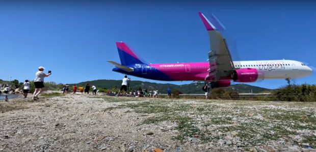 Momentul în care un avion de pasageri aterizează pe o insulă grecească, trecând la câțiva metri deasupra turiștilor