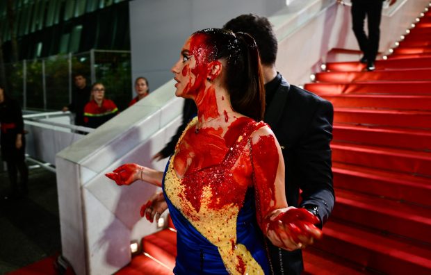 Protest pe covorul roșu de la Cannes. O femeie îmbrăcată în culorile steagului ucrainean s-a stropit de sânge fals