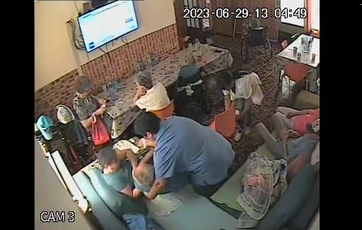 Captură de pe înregistrarea video. Una dintre infirmiere își pierde echilibrul când îl așază pe bătrân pe canapea