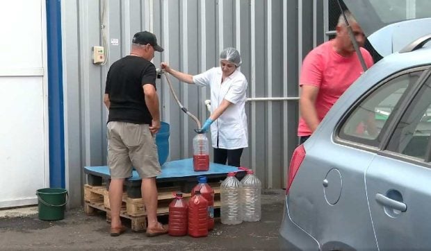 Zeci de oameni stau la coadă să ia suc de roșii proaspăt cu bidonul, direct din conducta fabricii, la Buzău: „Avem tot anul” | VIDEO