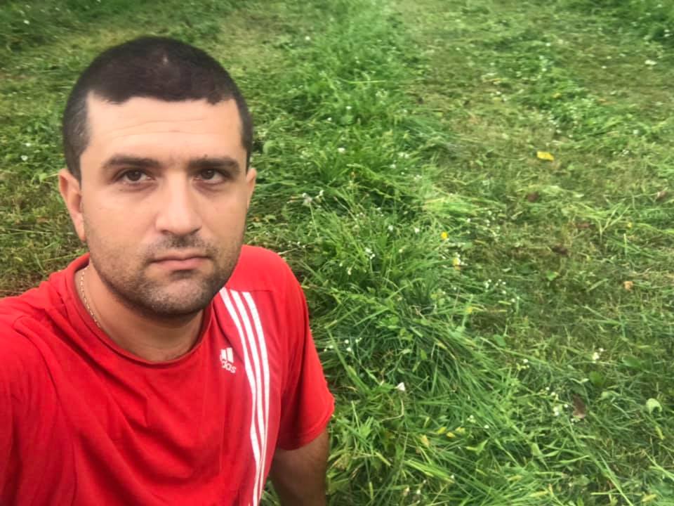 Un tanar imbracat în tricou rosu pe un gazon verde
