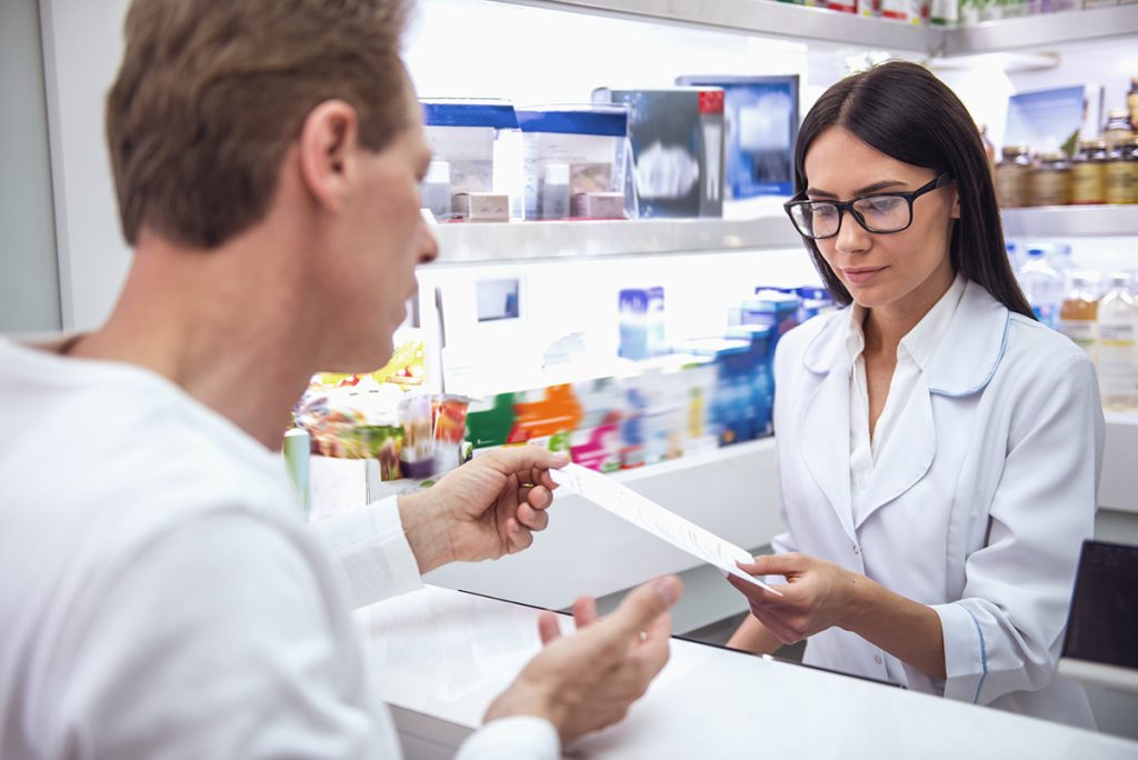 O farmacista citeste o reteta medicala a unui pacient intr-o farmacie
