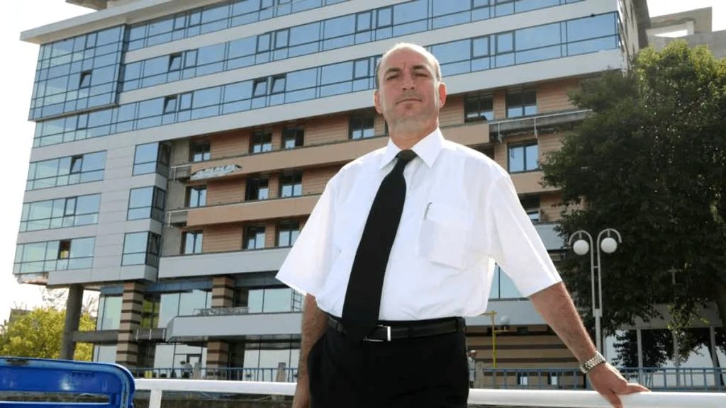 Un barbat în camasa alba in fata unei cladiri