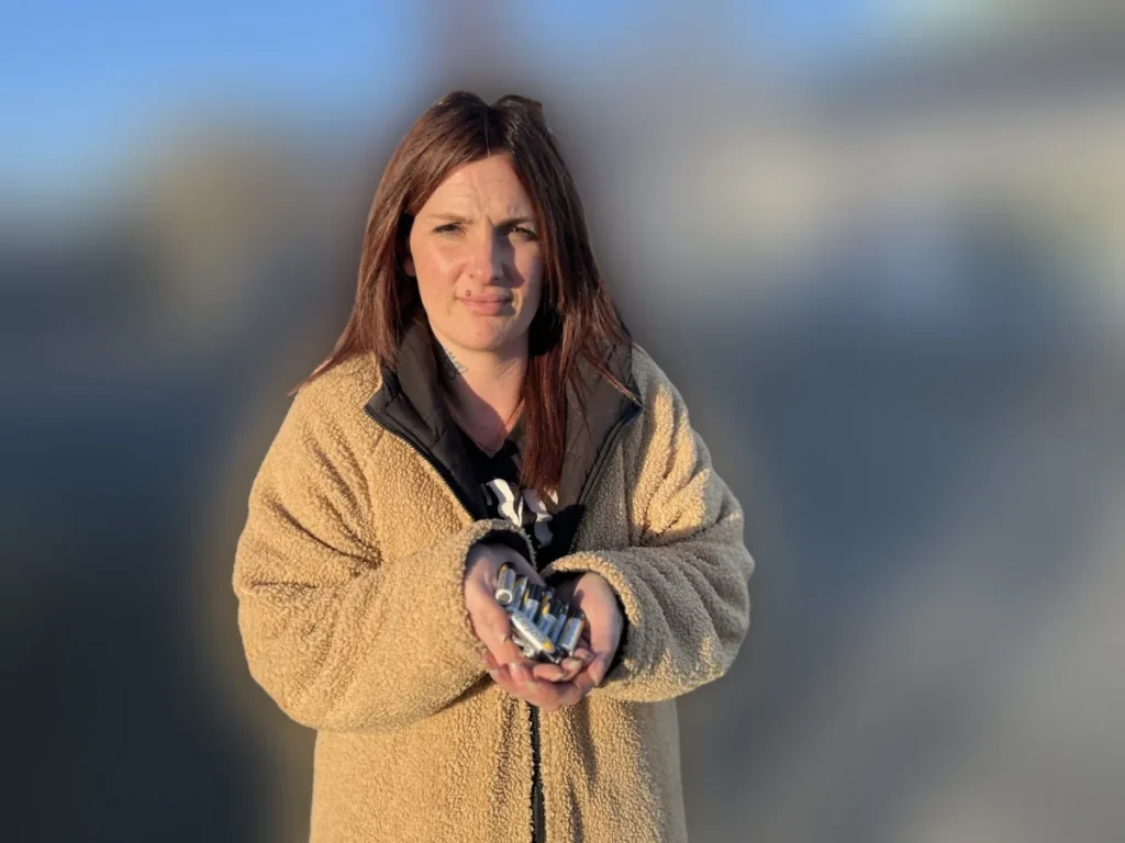 O femeie cu un palton bej tine in mama mai multe baterii 