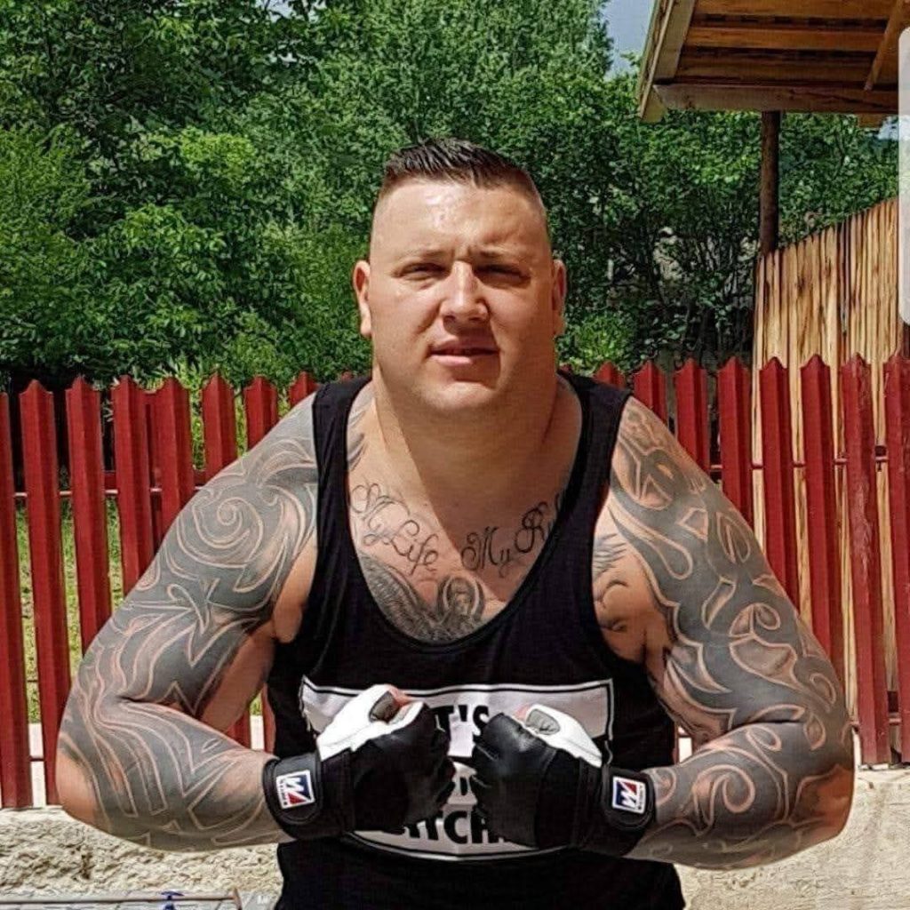 Un luptator MMA in tricou negru si multe tautaje
