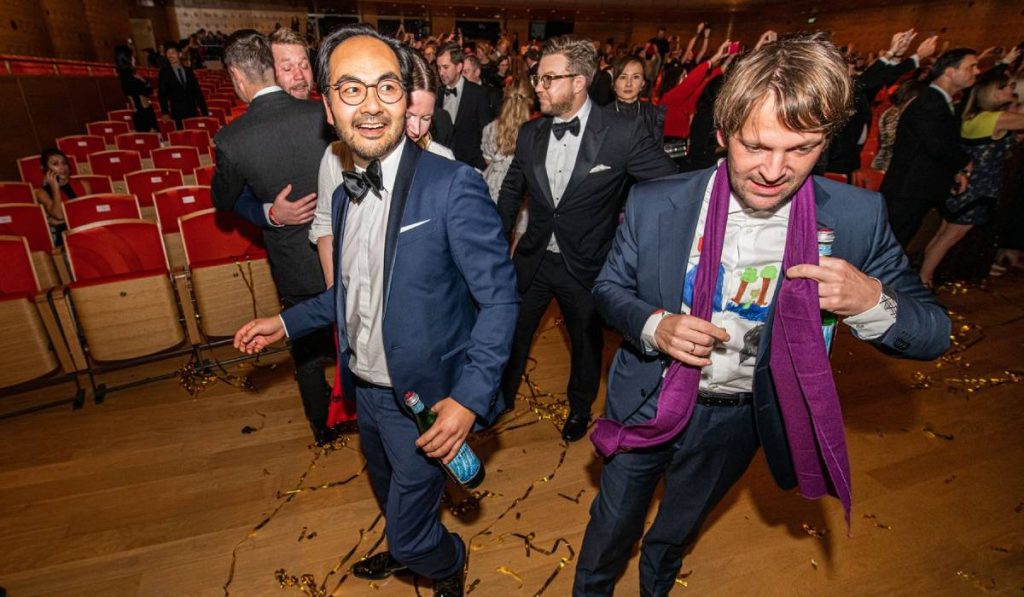 Bucătarul-șef René Redzepi de la Noma (dreapta), cu o esarfa mov la gat, in jurul lui foarte multi oameni, fotografiat după ce a câștigat premiul pentru cel mai bun restaurant la ceremonia de premiere „Cele mai bune 50 de restaurante din lume 2021”, la Anvers, marți, 5 octombrie 2021. 
