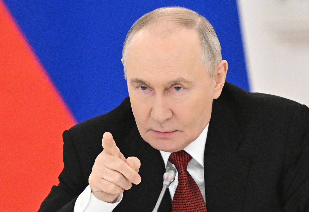 Vladimir Putin in costum negru aratând amenintator cu degetul
